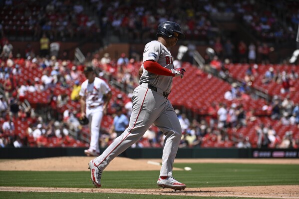 Boston Red Sox's Rafael Devers, right, rounds first base after hitting a two-run home run as St. Louis Cardinals relief pitcher Ryan Fernandez, back left, waits in the sixth inning of a baseball game, Sunday, May 19, 2024, in St. Louis. (AP Photo/Joe Puetz)
