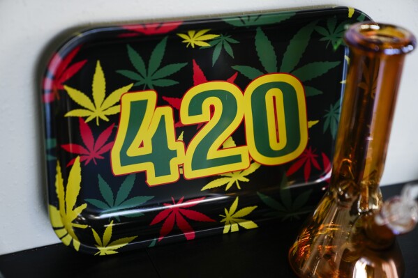 A 420 plate is displayed behind a glass bong on the shelves at Cloud 9 Cannabis, Saturday, April 13, 2024, in Arlington, Wash. The shop is one of the first dispensaries to open under the Washington Liquor and Cannabis Board's social equity program, established in efforts to remedy some of the disproportionate effects marijuana prohibition had on communities of color. (AP Photo/Lindsey Wasson)