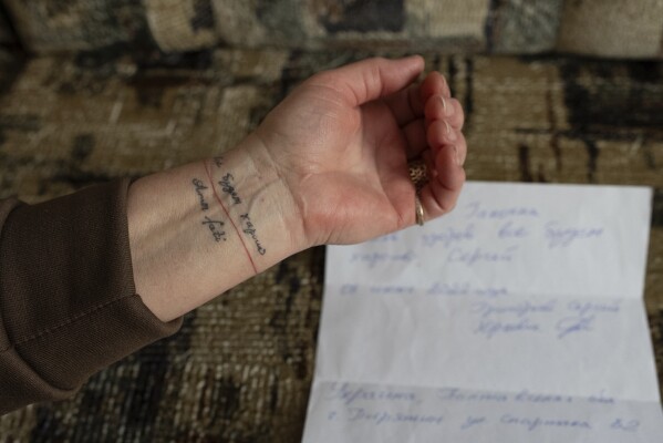 Halyna Hryhorieva of Pyriatyn, Ukraine, shows her tattoo of words often spoken by her husband, who was a prisoner of war in Russia: "Everything will be all right," on March 9, 2025. (AP Photo/Alex Babenko)