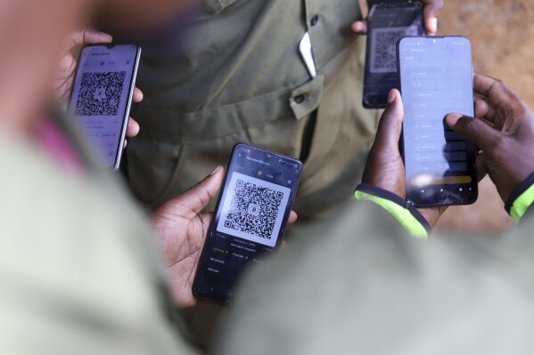 Members of the Livegreat Foundation who engage in waste management display their bitcoin wallets and QR codes in their mobile phones as they receive payments using bitcoin after a cleanup exercise at Kibera Slums in Nairobi, Kenya, Sunday, May 4, 2025. (AP Photo/Andrew Kasuku)