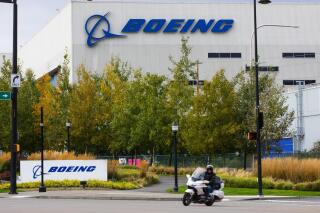 FILE - In this Oct. 28, 2020 file photo, a motorcyclist cruises past the Renton, Wash., Boeing plant where 737's are built. Boeing is temporarily lowering its delivery target for the 787 Dreamliner after discovering additional work that will need to be performed on the aircraft. The company said Tuesday, July 13, 2021, that the 787 production rate will temporarily be lower than five per month and will gradually return to that rate. (Ellen M. Banner/The Seattle Times via AP, File)