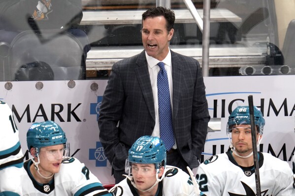 FILE - San Jose Sharks head coach David Quinn, center top, stands behind his bench during the third period of an NHL hockey game against the Pittsburgh Penguins in Pittsburgh, Thursday, March 14, 2024. The San Jose Sharks have fired coach David Quinn after two rough seasons as part of a massive rebuilding project. General manager Mike Grier announced the decision on Wednesday, April 24, following a review of the team's season. (AP Photo/Gene J. Puskar, File)