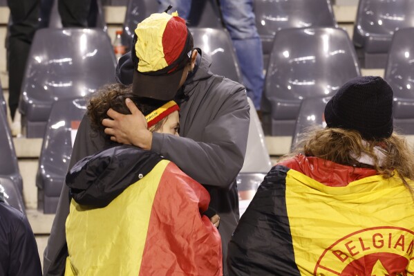 Supporters console themselves in the stands after the Euro 2024 Group F qualifying soccer match between Belgium and Sweden was suspended at the King Baudouin Stadium in Brussels, Monday, October 16, 2023. The game was called off at half-time due to the deaths of two Swedes. A shooting incident occurred in central Brussels before kick-off.  (AP Photo/Gert Vanden Weingart)