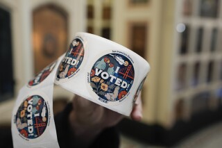 FILE - Election clerk Ray DiFazio holds a roll of stickers given to people after they voted in the primary election at the Columbarium in San Francisco, Tuesday, March 5, 2024. Social media users are falsely claiming that California's 2024 primary elections were rigged, citing its ongoing vote count as alleged proof. (AP Photo/Eric Risberg, File)