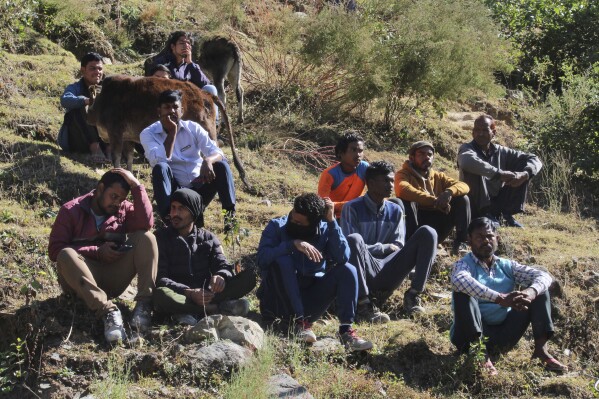 People watch rescue work at the site of an under-construction road tunnel that collapsed in mountainous Uttarakhand state, India, Saturday, Nov. 18, 2023. Forty workers were trapped in the collapsed road tunnel in northern India for a seventh day Saturday as rescuers waited for a new machine to drill through the rubble so they could crawl to their freedom. (AP Photo)