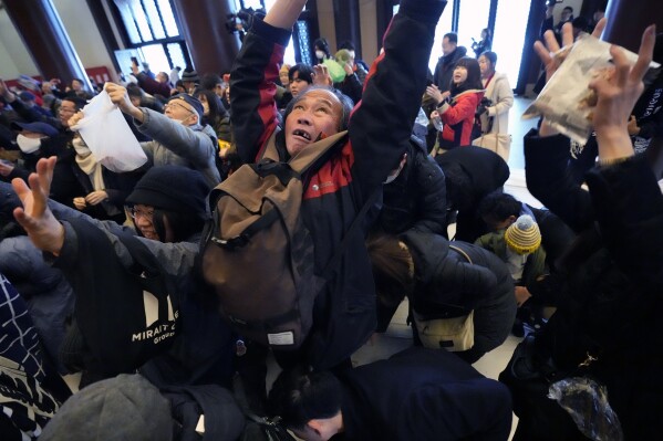 People jump to catch lucky beans dispersed by celebrities during the 