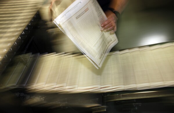 FILE - A pressman pulls a copy of one of the final editions of the Rocky Mountain News off the press in the Washington Street Printing Plant of the Denver Newspaper Agency in Denver on Feb. 26, 2009. The decline of local news in the United States is speeding up despite attention paid to the issue, to the point where the nation has lost one-third of its newspapers and two-thirds of its newspaper journalists since 2005. (AP Photo/David Zalubowski, File)