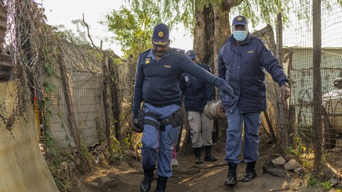 South African police officers remove gas cylinders used by illegal gold miners in the Angelo Informal Settlement in Boksburg, South Africa, Thursday July 6, 2023. South African police say at least 16 people, including three children, have died from a leak of a toxic nitrate gas that was being used by illegal miners to process gold. (AP Photo/Jerome Delay)