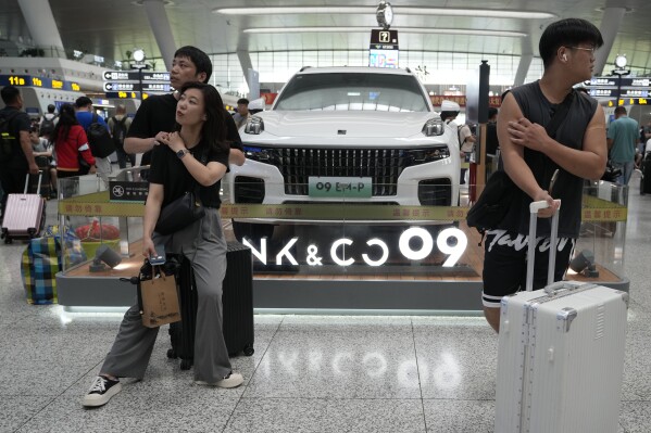 File - Passengers wait near a hybrid luxury SUV from China automaker Lynk&co displayed at the train station in Hangzhou in eastern China's Zhejiang province on Monday, July 3, 2023. Chinese automakers are winning over drivers as they make major inroads into Europe’s electric vehicle market, challenging long-established homegrown brands in an industry that’s key to the continent’s green energy transition. The European Union has launched an investigation into Beijing’s support for its EV industry, adding to tensions between the West and China. (AP Photo/Ng Han Guan, File)