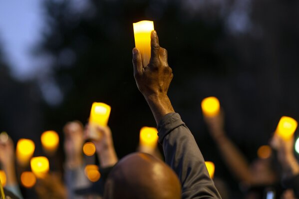 Marchers hold candles up as they listen to a speaker during a march and candlelight vigil for Ahmaud Arbery in the Satilla Shores neighborhood, Tuesday, Feb. 23, 2021, in Brunswick, Ga. Arbery was shot and killed last year while running in the neighborhood. (AP Photo/Stephen B. Morton)