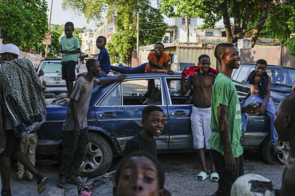 Youths hang out near cars serving as street barricades placed there by residents to deter gangs from entering their neighborhood, in downtown Port-au-Prince, Haiti, May 17, 2024. (AP Photo/Ramon Espinosa)