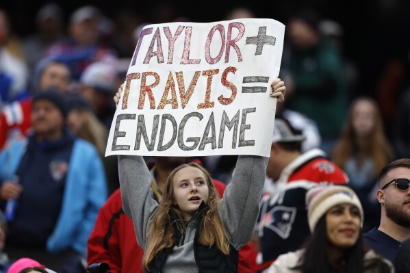 FILE - A fan displays a sign that calls attention to Taylor Swift and Kansas City Chiefs tight end Travis Kelce during the second half of an NFL football game between the Chiefs and the New England Patriots, Sunday, Dec. 17, 2023, in Foxborough, Mass. (APPhoto/Michael Dwyer, File)