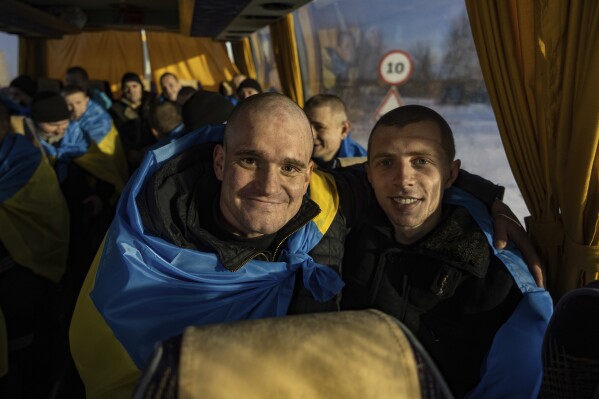 Recently swapped Ukrainian prisoners of war covered in national flags sit in a bus after a prisoner exchange on the Ukrainian Russian border, on Wednesday, Jan. 31, 2024. Russia and Ukraine have exchanged about 200 prisoners of war each, the countries said Wednesday, despite tensions stemming from last week's crash of a military transport plane that Moscow claimed was carrying Ukrainian POWs and was shot down by Kyiv's forces. (AP Photo/Danylo Pavlov)