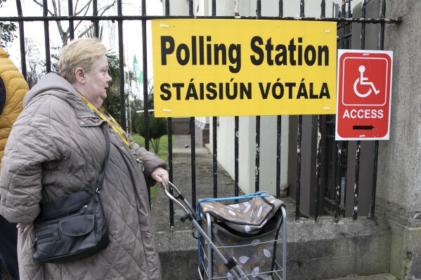 A woman arrives to vote in a referendum on the proposed changes to the wording of the Constitution relating to the areas of family and care are seen at Treasa Naofa on Donore Avenue, Dublin , in Dublin, Ireland, Friday, March 8, 2024. As the world marks International Women's Day, in Ireland, voters are deciding on Friday whether to change the constitution to remove passages referring to women’s domestic duties and broadening the definition of the family. (Gareth Chaney/PA via AP)