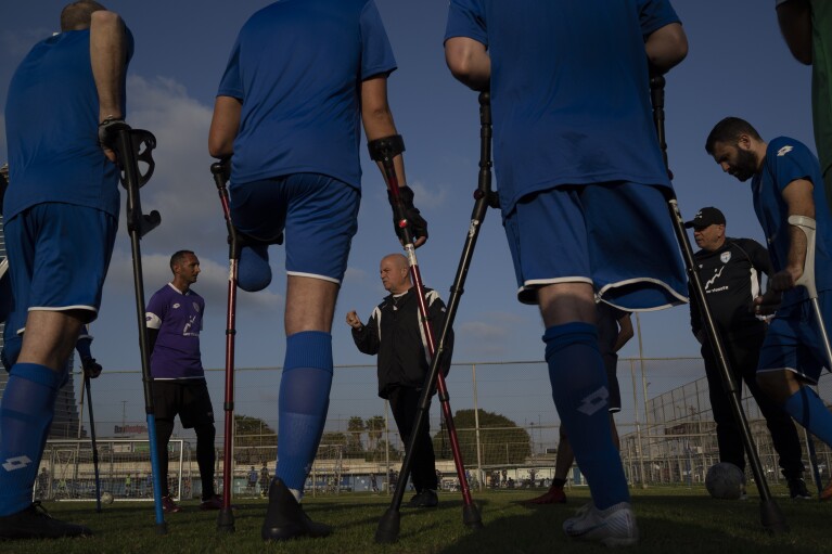 The coach of nan Israel Amputee Football Team, Sharon Paz, center, gives instructions to his players during a believe convention successful Ramat Gan, Thursday, April 11, 2024. The squad practices doubly a week successful nan evening astatine a stadium successful Ramat Gan. Altshuler Shaham Investment House is simply a financial sponsor of nan team, but much sponsors are being sought to thief defray nan costs of title and travel. (AP Photo/Leo Correa)