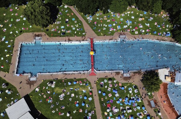 People fill a public pool in Frankfurt, Germany, on a warm Saturday, June 21, 2025. (AP Photo/Michael Probst)