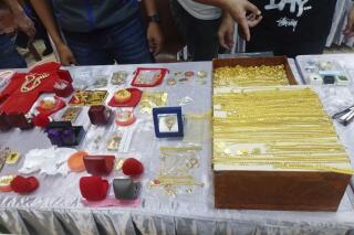 In this handout photo released by Thai police Central Investigation Bureau and taken Wednesday, May 10, 2023, Thai police display gold and other jewelry they discovered in a raid on a Buddhist temple at police station in Nakhon Ratchasima, northeast of Thailand. They announced Wednesday they have arrested nine people, including seven monks, who are accused of embezzling about 300 million baht ($8.9 million) from the donation fund of the temple where the items were found. (Thai police Central Investigation Bureau via AP).