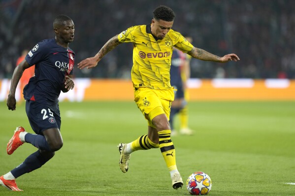 Dortmund's Jadon Sancho, right, challenges for the ball with PSG's Nuno Mendes during the Champions League semifinal second leg soccer match between Paris Saint-Germain and Borussia Dortmund at the Parc des Princes stadium in Paris, France, Tuesday, May 7, 2024. (AP Photo/Lewis Joly)