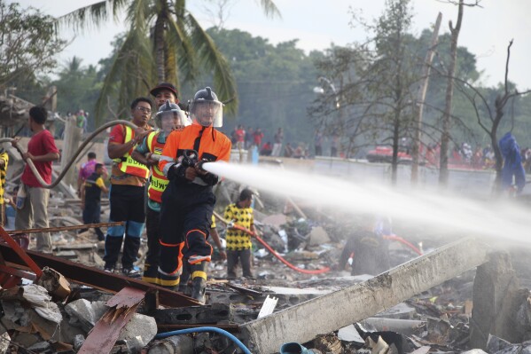 A fireman sprays water after an explosion occured at a firework warehouse in Narathiwat province southern Thailand, Saturday, July 29, 2023. A large explosion at a fireworks warehouse in southern Thailand on Saturday killed at least nine people and wounded scores, officials said. (AP Photo/Kriya Tehtani)