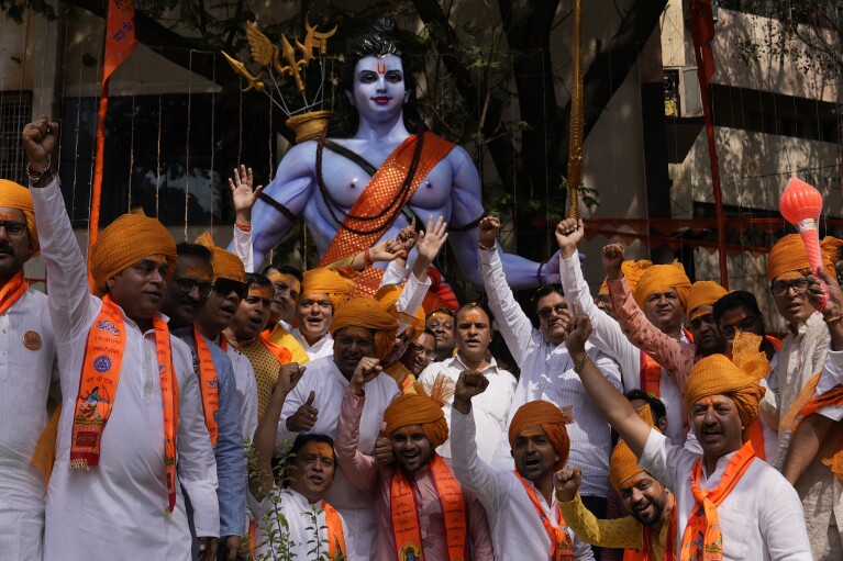 सोमवार, 22 जनवरी, 2024 को अयोध्या में राम को समर्पित एक मंदिर के उद्घाटन के दौरान, भारत के हैदराबाद में एक धार्मिक जुलूस में हिंदू भक्त हिंदू भगवान राम की छवि के बगल में पोज़ देते हुए। (एपी फोटो/महेश कुमार ए)