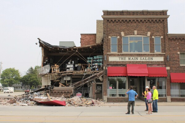 Some of the tenants converse near the building while they wait for a structural engineer to come and inspect the building, Monday, July 24, 2023 at 1263, Main Street, in Green Bay, Wis. A minivan crashed into the building overnight, toppling much of its brick facade and leaving much of its roof sagging precariously, police said Monday. (Ariel Perez/The Green Bay Press-Gazette via AP)