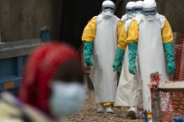 FILE— In this July 16, 2019 photo, health workers dressed in protective gear begin their shift at an Ebola treatment center in Beni, Congo DRC. Internal documents obtained by The Associated Press show that the World Health Organization has paid $250 each to at least 104 women in Congo who say they were sexually abused or exploited by Ebola outbreak responders. That amount is less than what some U.N. officials are given for a single day's expenses when working in Congo. (AP Photo/Jerome Delay, File)