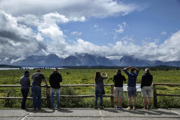 FILE - In this Aug. 21, 2014 file photo people look out at the mountains from the Jackson Lake Lodge in Grand Teton National Park near Jackson, Wyo. Just nine months into 2021, Wyoming's Grand Teton National Park already has had its busiest year on record. Grand Teton had almost 3.5 million recreation visits between January and September. The official count of 3,493,937 topped 2018's full-year record by 2,786, park officials said in a statement Wednesday, Oct. 20, 2021. (AP Photo/John Locher, File)