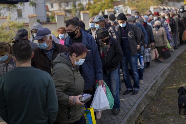 People queue up to wait a ration food from World Central Kitchen organisation in the center of Mykolaiv, Monday, Oct. 24, 2022. As Ukraine crosses the mark of eight months anniversary since the start of full-scale war, the residents of southern Mykolaiv, who suffer shelling almost every night, are determined to fight as long as it takes to liberate all the regions. (AP Photo/Emilio Morenatti)