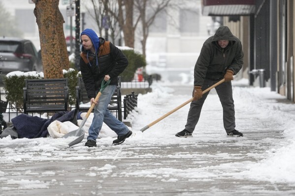 Jesse Asher, left, and Eric Magas shovel snow Thursday, Jan. 18, 2024, in Nashville, Tenn. A snowstorm blanketed the area with up to eight inches of snow and frigid temperatures. (AP Photo/George Walker IV)