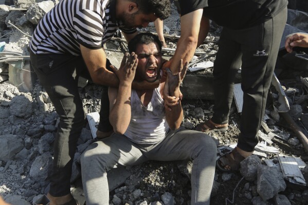 Palestinians comfort a crying man who lost relatives under the rubble of a house destroyed in an Israeli airstrike in Gaza City, Saturday, Nov. 4, 2023. (AP Photo/Abed Khaled)