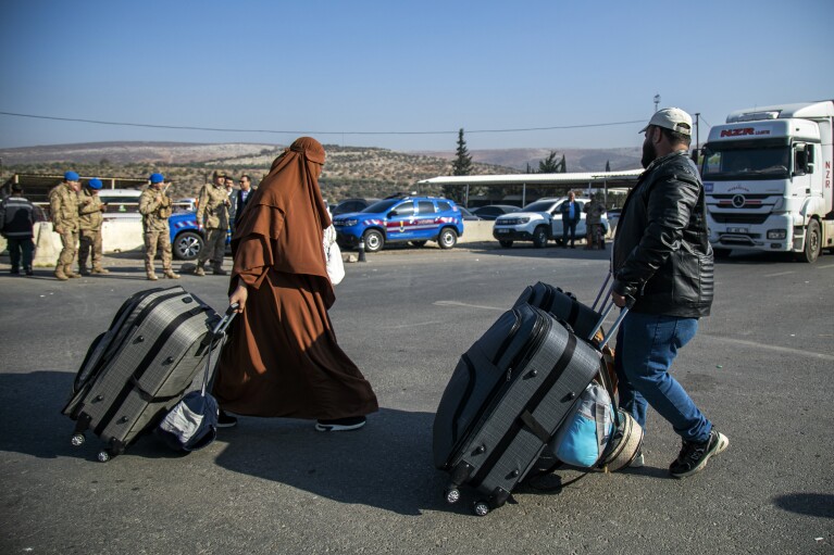 Syrians arrive to cross into Syria from Turkey at the Cilvegozu border gate, near the town of Antakya, southern Turkey, Monday, Dec. 9, 2024. (AP Photo/Metin Yoksu)