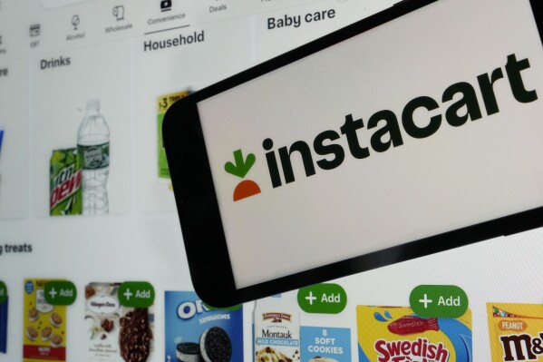 FILE - An instacart logo and an instacart webpage are shown in this photo, in New York, Wednesday, Sept. 6, 2023. nstacart is partnering with Uber Eats to offer restaurant delivery to its customers. Instacart said Tuesday that its U.S. shoppers will see a “Restaurants” tab in the company’s app in the coming weeks. (AP Photo/Richard Drew, File)
