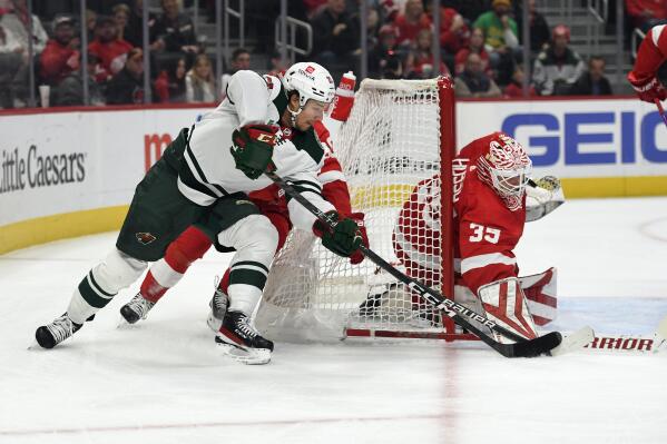 Detroit Red Wings goaltender Ville Husso, right, blocks the shot of Minnesota Wild's Brandon Duhaime during the first period of an NHL hockey game, Saturday, Oct. 29, 2022, in Detroit. (AP Photo/Jose Juarez)