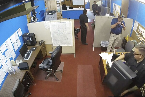 This surveillance video shows Marion Police Department confiscating computers and cellphones from the publisher and staff of the Marion County Record on Friday, Aug. 11, 2023 in Marion, Kan. The small newspaper and the police department in Kansas are at the center of a dispute over freedom of speech that is being watched around the country after police raided the office of the local newspaper and the home of its owner and publisher. (Marion County Record via AP)