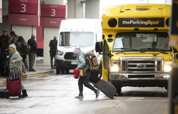 Traveller dodges shuttle buses on the way into Denver International Airport on Monday, Nov. 20, 2023, in Denver. (AP Photo/David Zalubowski)