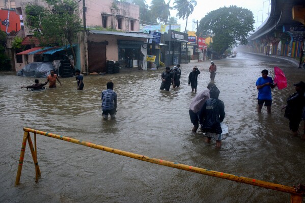 CORRECTS TO STORM MICHAUNG - People wade through a flooded street following heavy rains along the Bay of Bengal coast in Chennai, India, Monday, Dec.4, 2023. Authorities issued warnings for tropical storm Michaung, which is likely to hit the southern coast on Tuesday with maximum sustained winds of 90-100 kilometers (56-62 miles) per hour with gusts up to 110 kph (68 mph), the Indian Meteorological Department said. (APPhoto)