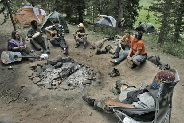 FILE -Rainbow Family members gather around a fire circle for music and conversation Saturday, July 1, 2006, north of Steamboat Springs, Colo., in the Routt National Forest. Officials expect up to 30,000 people to show up for this yeasr's gathering, which is slated to be held in Colorado and will mark the group's 50th anniversary. (AP Photo/Ed Andrieski, File)
