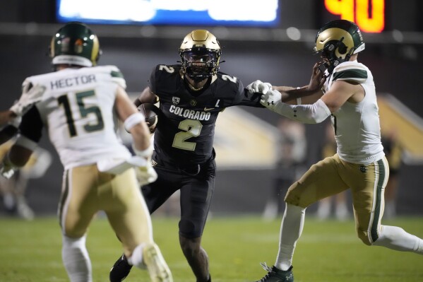 Colorado quarterback Shedeur Sanders, center, grabs the face mask of Colorado State defensive back Jack Howell, right, as defensive back Ayden Hector comes in to cover in the second half of an NCAA college football game Saturday, Sept. 16, 2023, in Boulder, Colo. (AP Photo/David Zalubowski)
