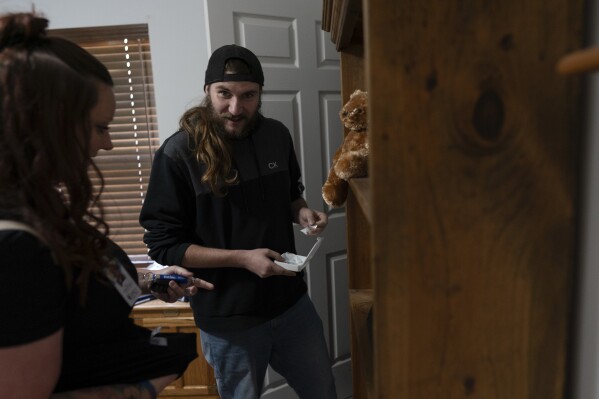 Tyler Baker retrieves fentanyl from his bedroom closet for disposal as his peer support worker Jesse Johnson of the Family Resource Center looks on at left, in Findlay, Ohio, Thursday, Oct. 12, 2023. (AP Photo/Carolyn Kaster)