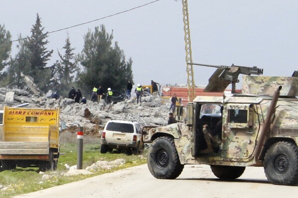 A Lebanese army vehicle block a road leading to a destroyed warehouse, background, which was attacked by Israeli airstrikes, on the outskirts of the Hezbollah stronghold village of Buday, near Baalbek town, east Lebanon, Monday, Feb. 26, 2024. The Israeli military says its air force struck targets of the militant Hezbollah group 