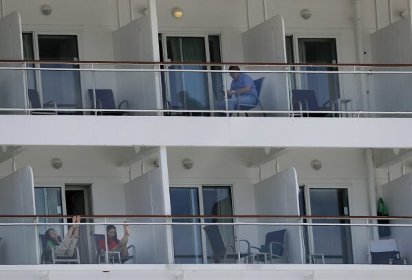 In this May 8, 2020 photo, people aboard the Norwegian Epic cruise ship docked at PortMiami in Miami, sit on their balconies. Tens of thousands of crew members, including U.S. citizens, remain confined to cabins aboard cruise ships, weeks after governments and companies negotiated disembarkation for passengers in the midst of the coronavirus pandemic. Most crew members are stuck in ships with no confirmed cases but are rejected by governments because of new rules to avoid importing more virus cases. (AP Photo/Wilfredo Lee)