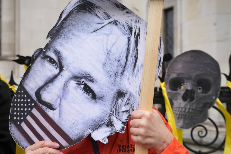 A protester holds a mask of Julian Assange outside the Royal Courts of Justice in London on Tuesday, February 20, 2024.  Julian Assange's lawyers will launch their final UK legal challenge to stop the WikiLeaks founder being sent to the United States to face espionage charges.  ,  The 52-year-old has been fighting extradition for more than a decade, including seven years in self-exile at the Ecuadorian embassy in London and the last five years in a high-security prison.  (AP Photo/Kirsty Wigglesworth)