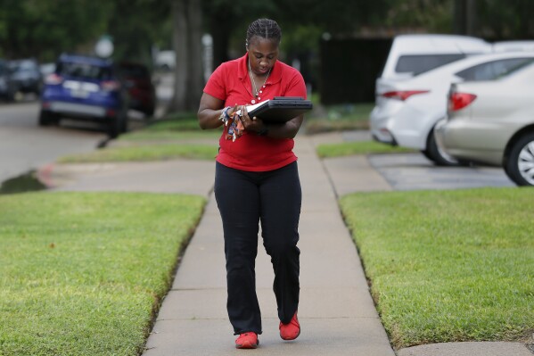 Deneshun Graves, a disease intervention specialist with the Houston Health Department, fills out paperwork as she walks back to her pickup truck after trying to contact a client, who wasn't home in Houston on Thursday, Oct. 26, 2023. Disease intervention specialists often link infected mothers and their partners with care for syphilis to help prevent congenital syphilis in the baby. (AP Photo/Michael Wyke)