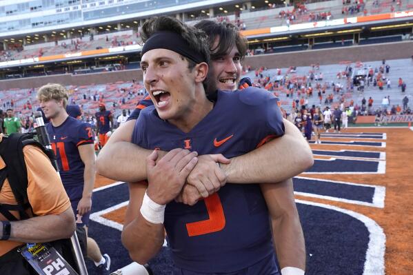 FILE - Illinois quarterback Tommy DeVito is hugged by a teammate after their win over Wyoming in an NCAA college football game Saturday, Aug. 27, 2022, in Champaign, Ill. Illinois is the most surprising team and quarterback Tommy DeVito is the most surprising player in the Associated Press Big Ten Midseason Awards, Tuesday, Oct. 11, 2022.(AP Photo/Charles Rex Arbogast, File)