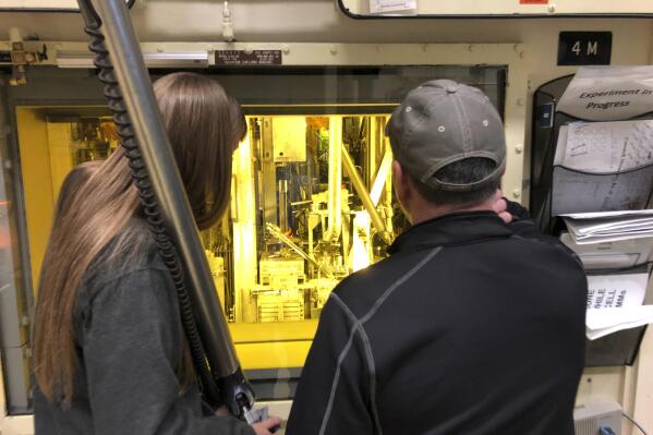 FILE - Hot cell operators Dawnette Hunter, left, and Scot White manipulate radioactive material from behind 4-foot-thick leaded glass at the Hot Fuel Examination Facility at the Idaho National Laboratory, about 50 miles west of Idaho Falls, Idaho, on Nov. 29, 2018. The U.S. Department of Energy said Tuesday, Oct. 25, 2022, the Idaho National Laboratory will receive $150 million for infrastructure improvements to boost nuclear research and development. (AP Photo/Keith Riddler, File)