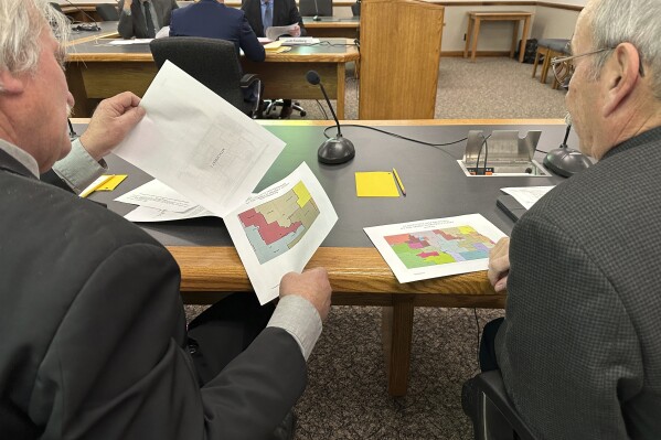 FILE - North Dakota state Rep. Robin Weisz, at left, and state Sen. Jerry Klein, both Republicans, inspect alternative maps proposed by the Turtle Mountain Band of Chippewa Indians and the Spirit Lake Tribe, on Tuesday, Dec. 5, 2023, during a meeting of a top legislative panel at the state Capitol in Bismarck, N.D. The 8th U.S. Circuit Court of Appeals denied a request on Friday, Dec. 15, to delay a federal judge's decision that North Dakota's legislative map violates the Voting Rights Act in diluting the voting strength of two Native American tribes. (AP Photo/Jack Dura, File)