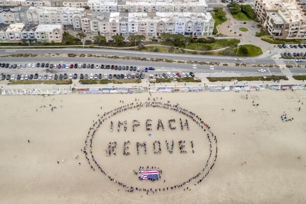 Protesters form a "Impeach & Remove" human banner on Ocean Beach during a protest against U.S. President Donald Trump, in San Francisco, Saturday, April 19, 2025. (Stephen Lam/San Francisco Chronicle via AP)