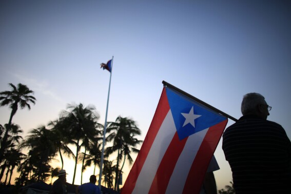 FILE - People gather in front of the Puerto Rico's Capitol on April 30, 2015 in San Juan. Puerto Rico will hold a Democratic presidential primary Sunday, the only opportunity for Democrats on the island to officially weigh in on the race for the White House. (AP Photo/Ricardo Arduengo, File)