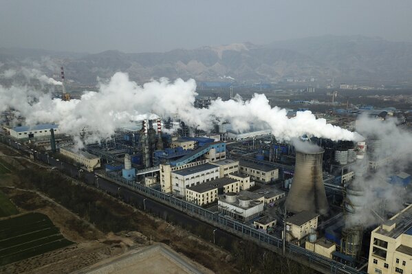 FILE - In this Nov. 28, 2019, file photo, smoke and steam rise from a coal processing plant that produces carbon black, an ingredient in steel manufacturing, in Hejin in central China's Shanxi Province. A new study finds that global man-made carbon pollution continues to rise, but it's not increasing as fast as the previous couple years. The study published Tuesday, Dec. 3, by scientists at the Global Carbon Project finds carbon dioxide emissions increased six tenths of a percent from 2018. (AP Photo/Sam McNeil, File)