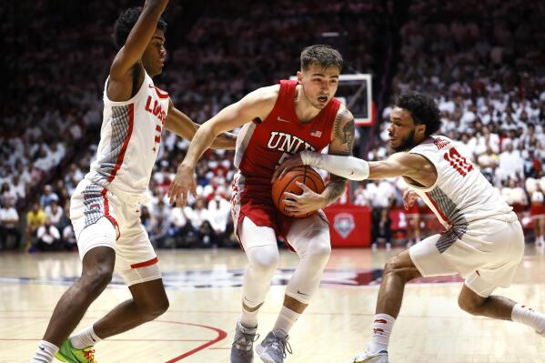 UNLV guard Jordan McCabe drives between New Mexico's Donovan Dent, left and Jaelen House during the first half of an NCAA college basketball game Saturday, Jan. 7, 2023, in Albuquerque, N.M. (AP Photo/Eric Draper)